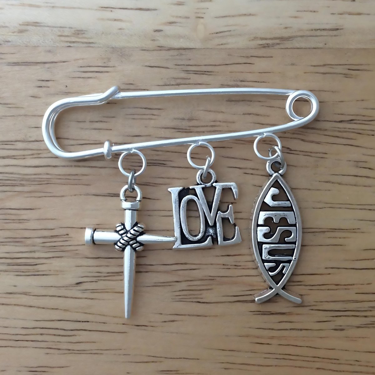 Lapel pin with a nail cross, love charm and Jesus fish charm