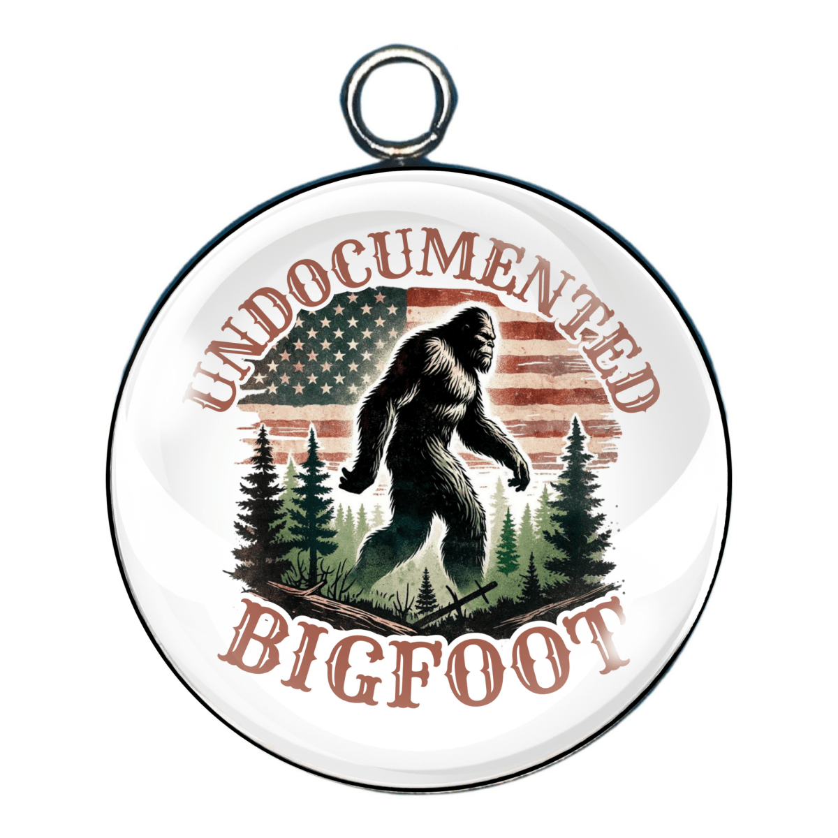 Charm reading “Undocumented Bigfoot,” with Bigfoot’s silhouette walking past trees and a rustic American flag in the background.