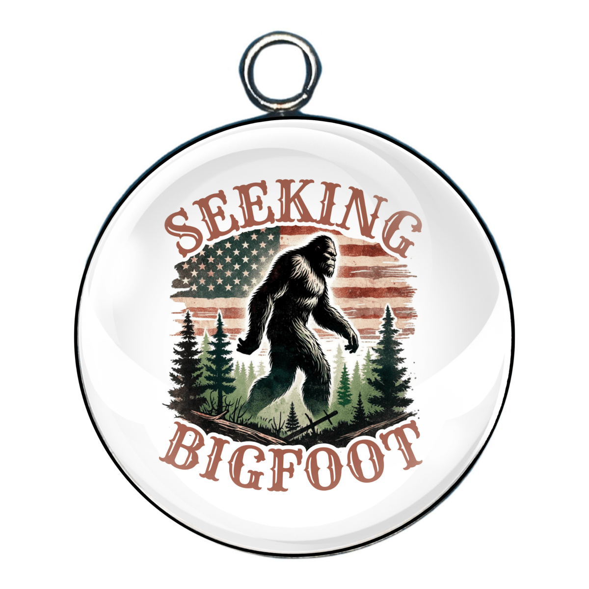 Round charm with the phrase “Seeking Bigfoot” featuring a silhouette of Bigfoot walking among pine trees and an American flag backdrop.