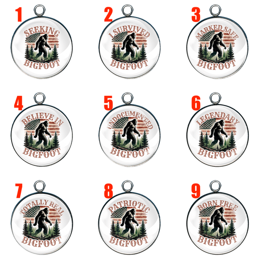 Image featuring 9 round Bigfoot-themed glass cabochon charms, each with a unique phrase and design, arranged in a 3x3 grid and numbered in red. Each charm features a silhouette of Bigfoot walking through a forest, with a rustic American flag background.
Charm 1 (Top row, left): "Seeking Bigfoot" – Bigfoot walking among pine trees.
Charm 2 (Top row, center): "I Survived Bigfoot" – Bigfoot in a forest with a flag behind.
Charm 3 (Top row, right): "Marked Safe Bigfoot" – Bigfoot near trees with patriotic elem