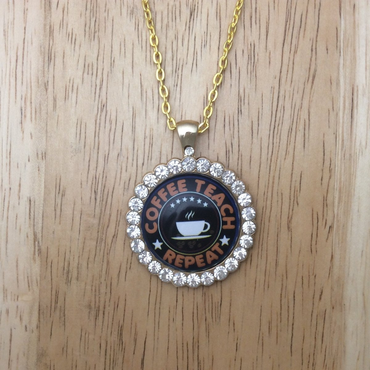 gold necklace with a gold jeweled glass cabochon pendant that says Coffee Teach Repeat.