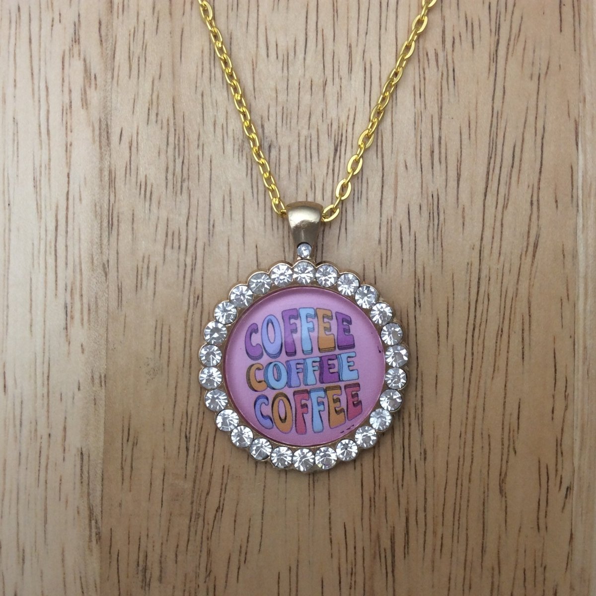 gold necklace with a gold jeweled glass cabochon pendant that says coffee coffee coffee