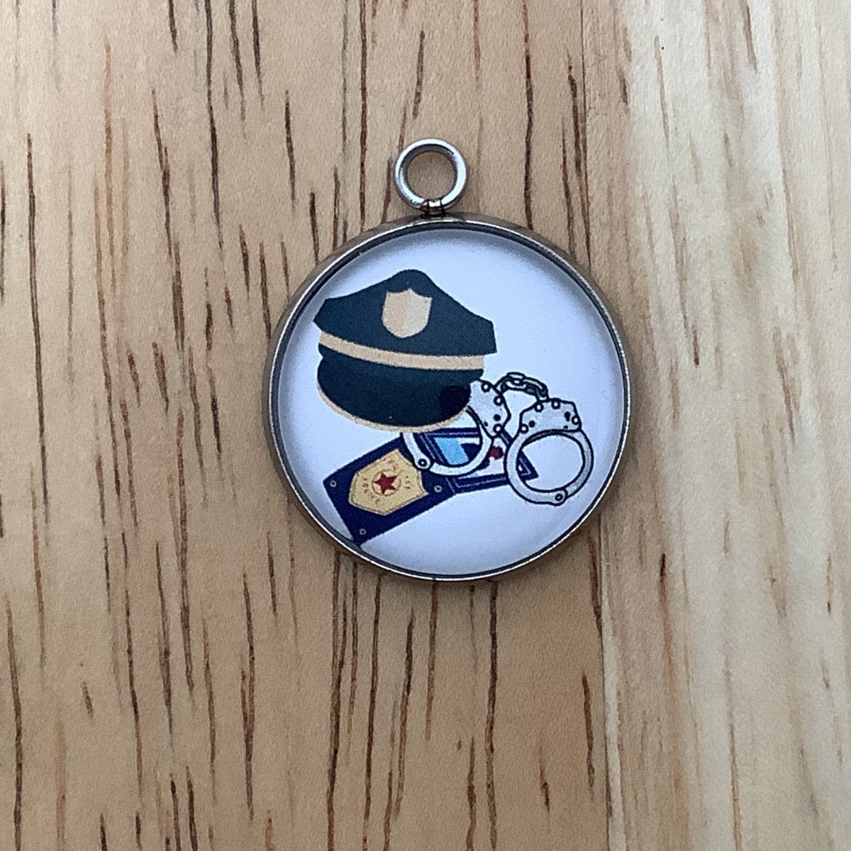 Charm featuring police gear: handcuffs, badge, and handcuffs