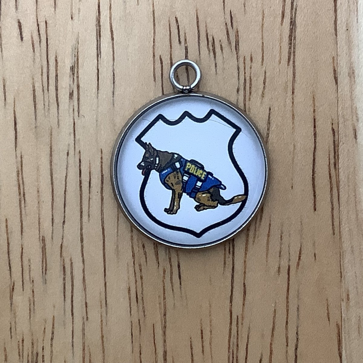 charm featuring a badge outline with a police dog