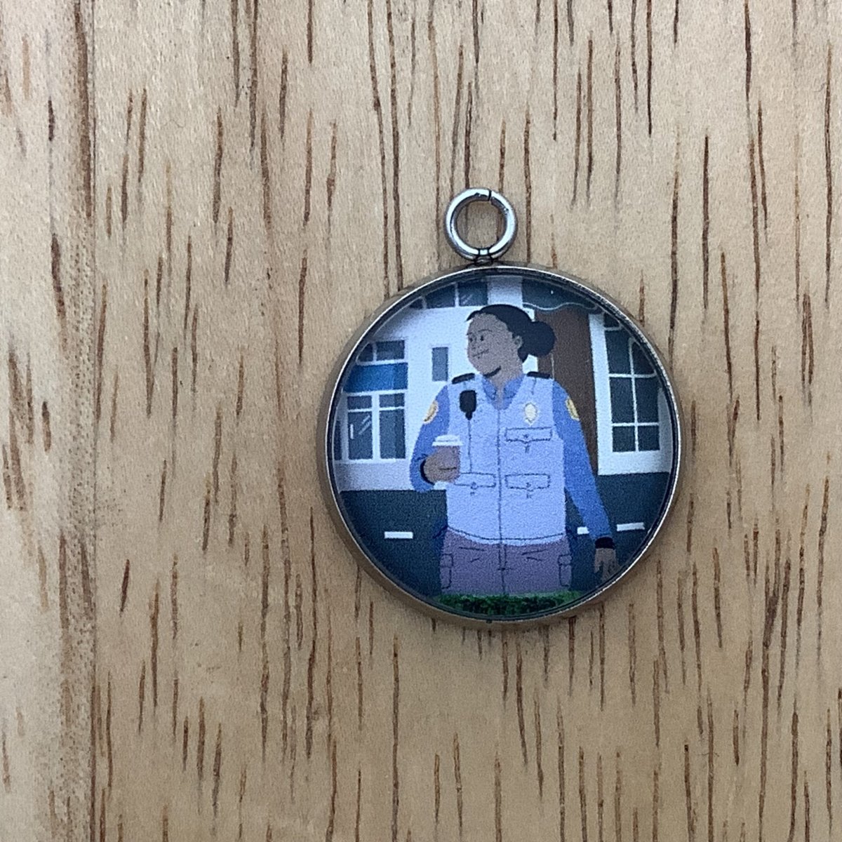 Charm depicting a police woman holding a cup of coffee