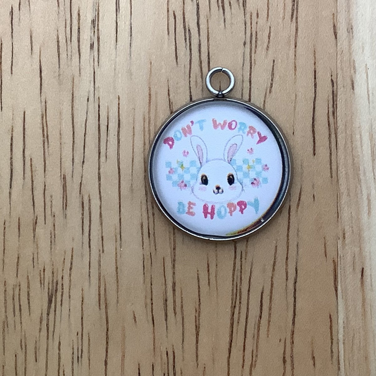 A bunny face with the words 'don't worry, be hoppy' written with a checked pattern and flowers in the background