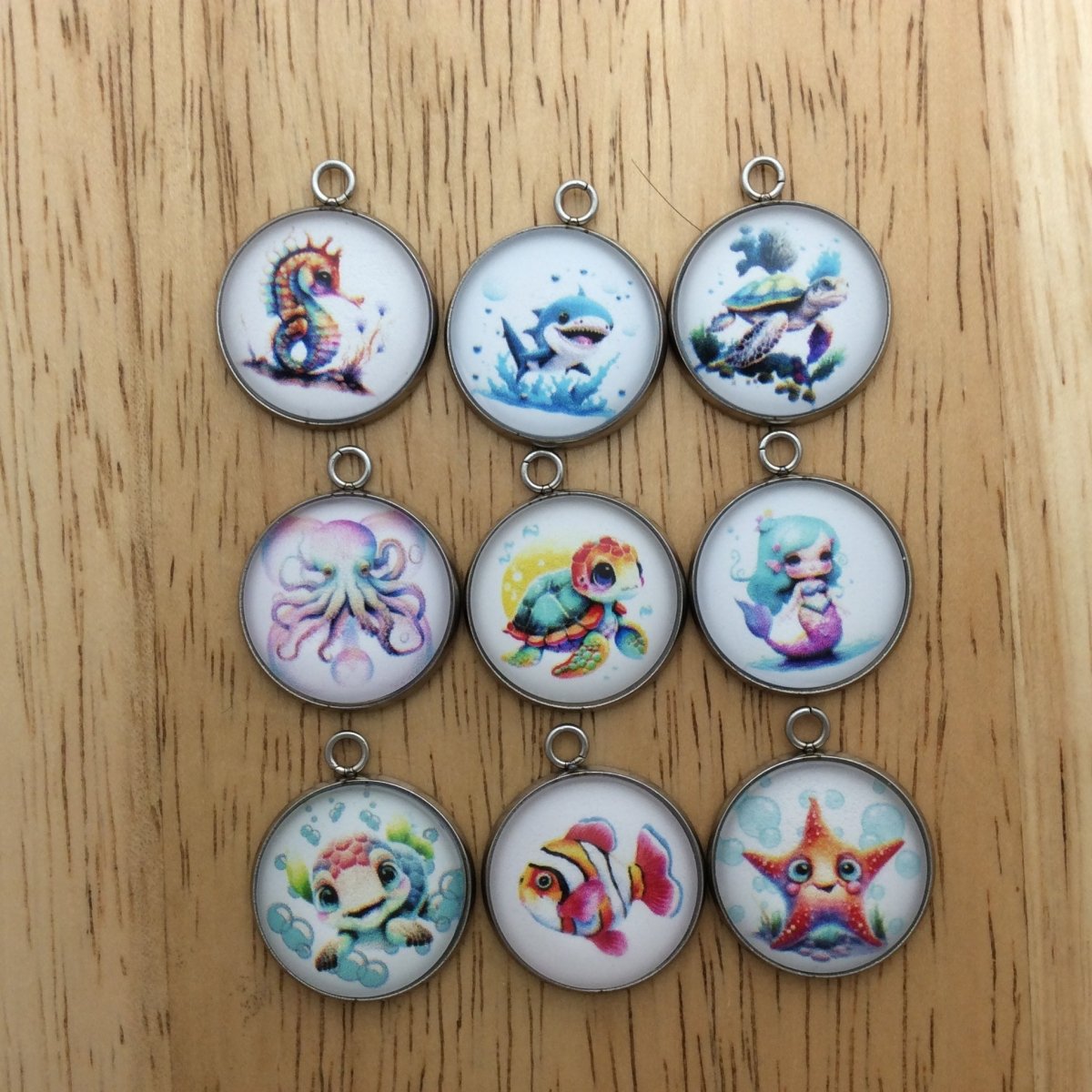 9 glass cabochon charms with images aof various saline creatures
