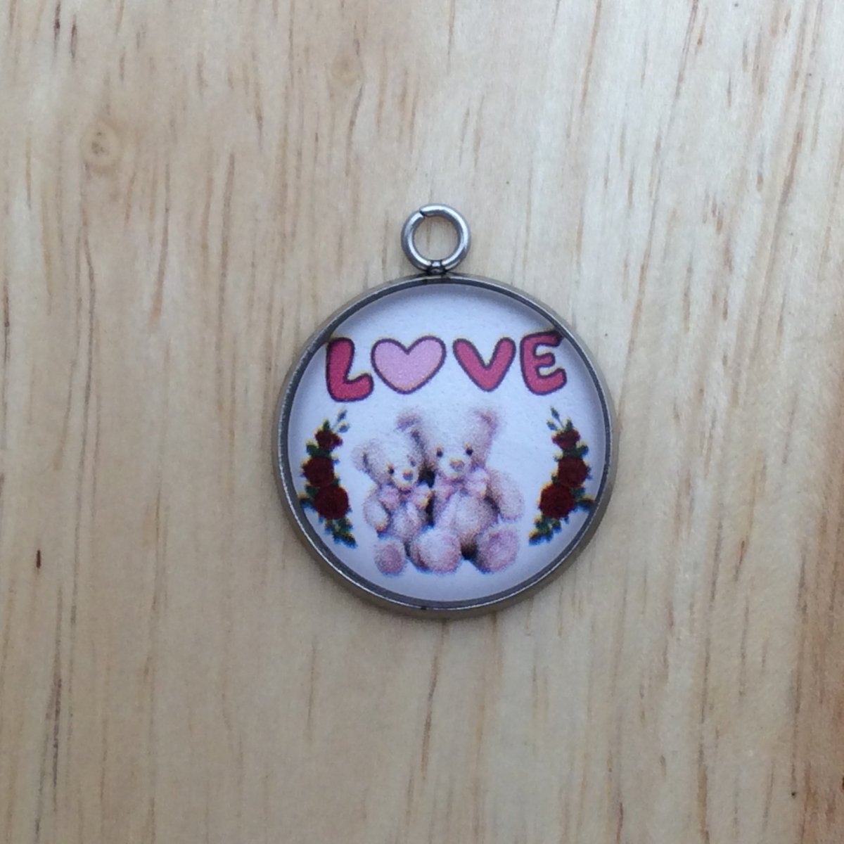 one glass cabochon charm with two sitting teddy bears between two rose vines with the word LOVE