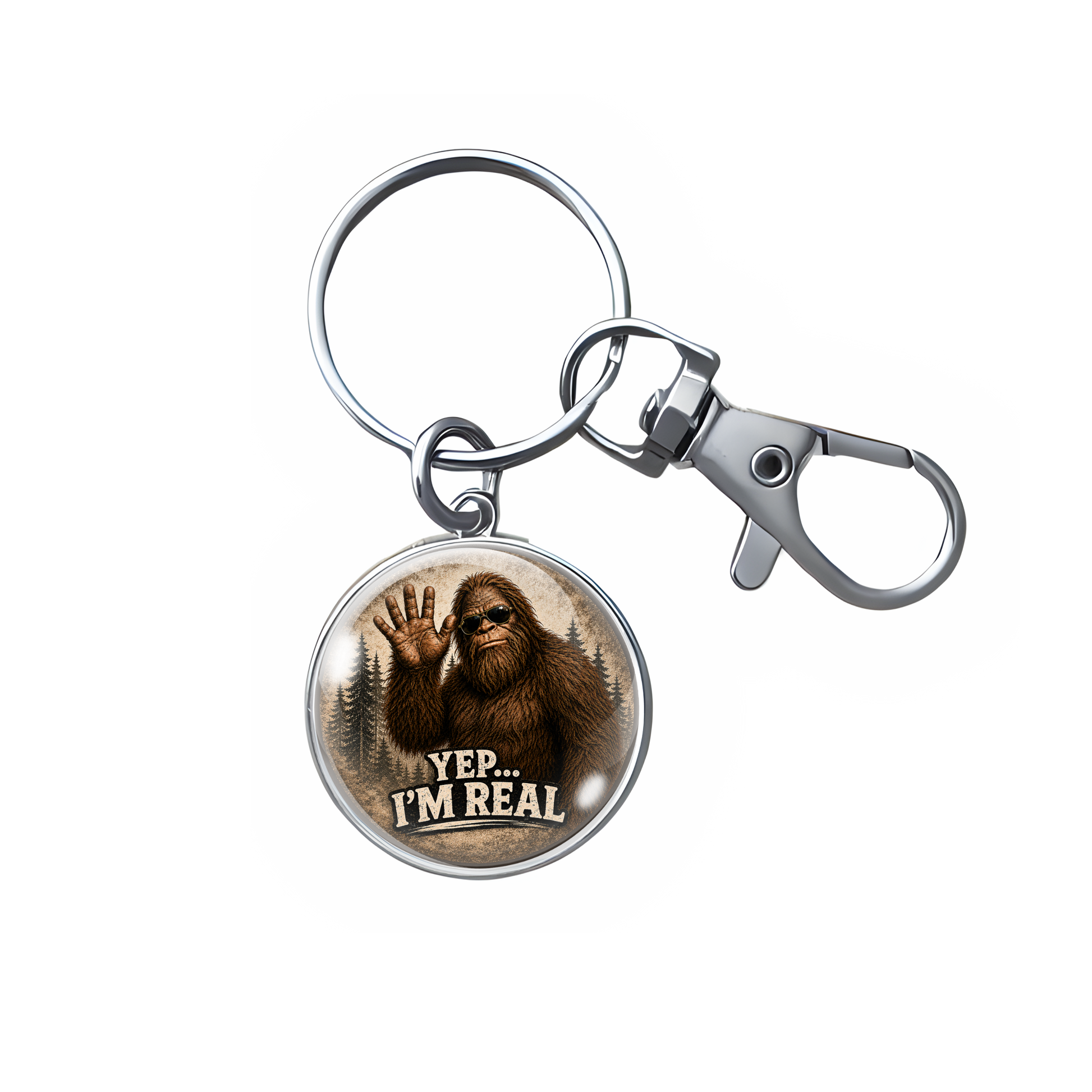 A silver metal keychain with a round glass-domed charm featuring an illustration of Bigfoot waving and the text 'YEP.