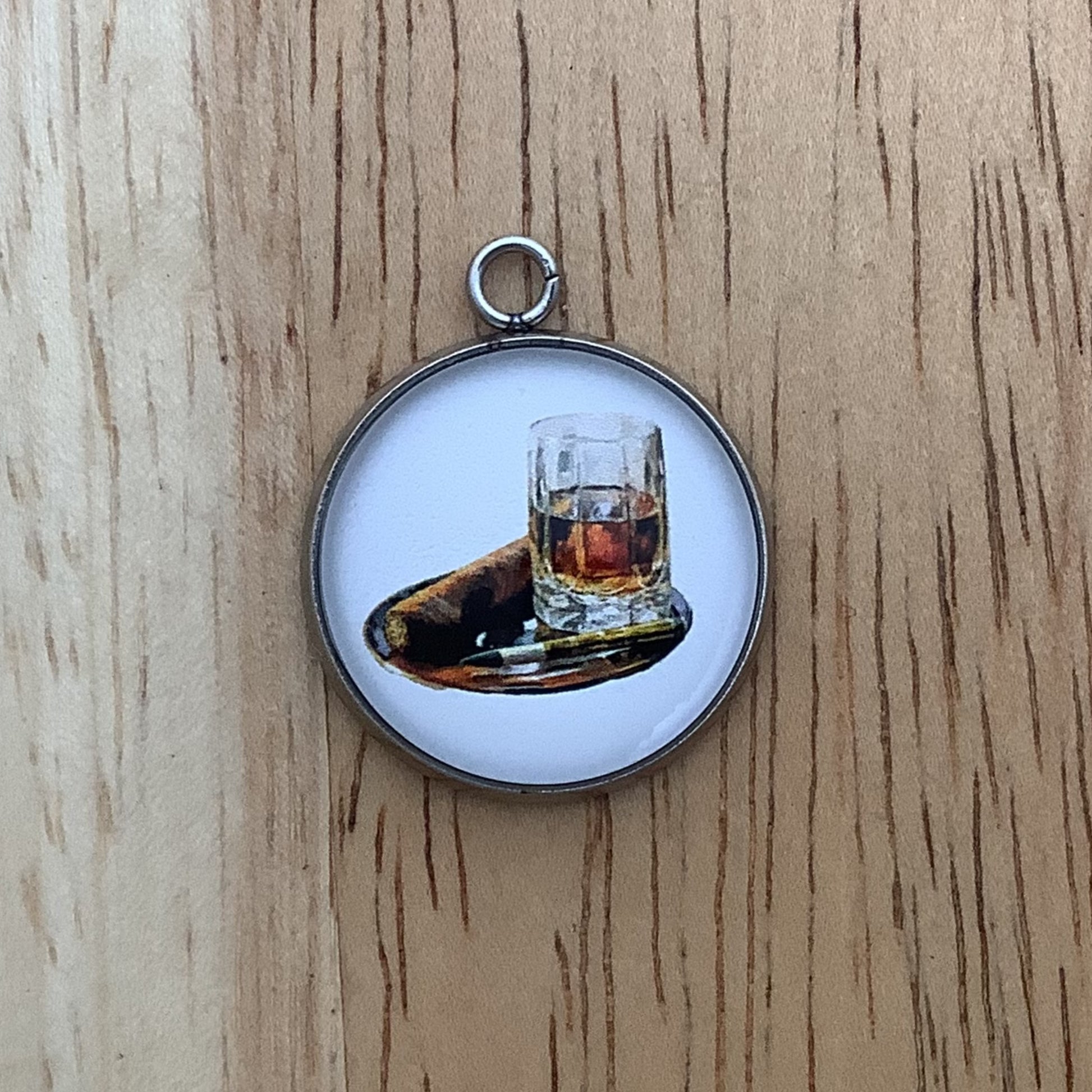 charm depicting a cigar and a bottle of brown liquors