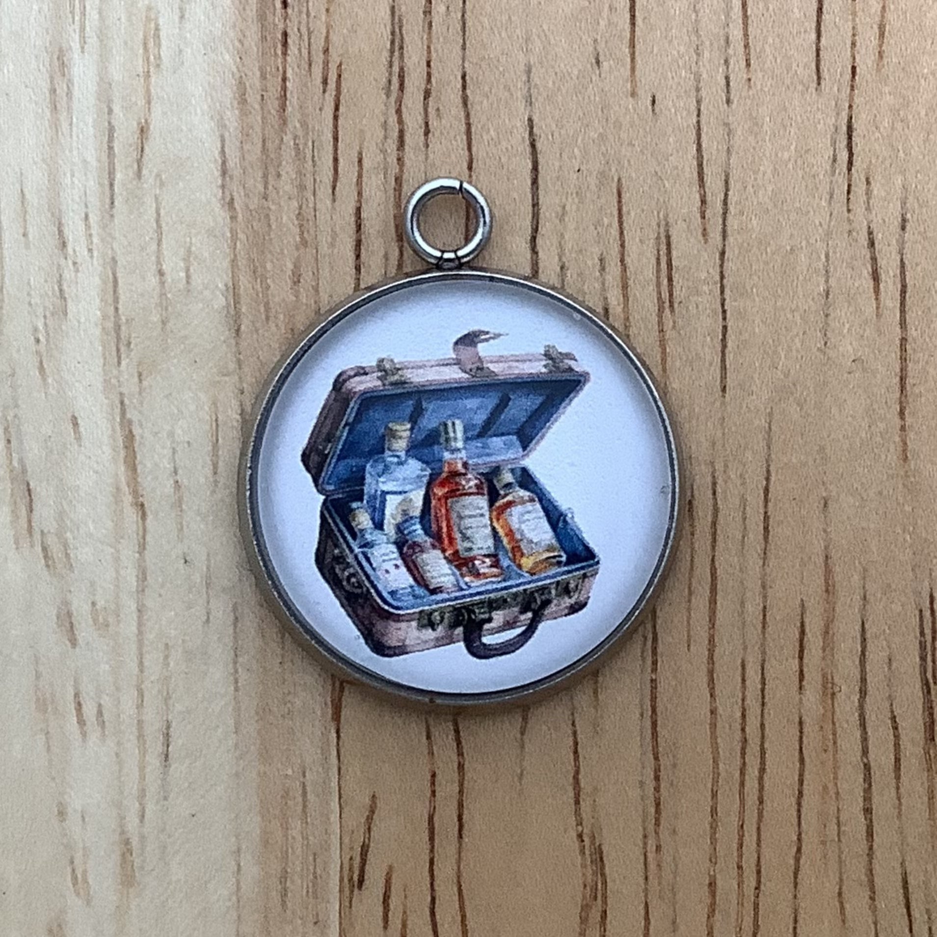 charm depicting a suitcase with bottles of liquor.