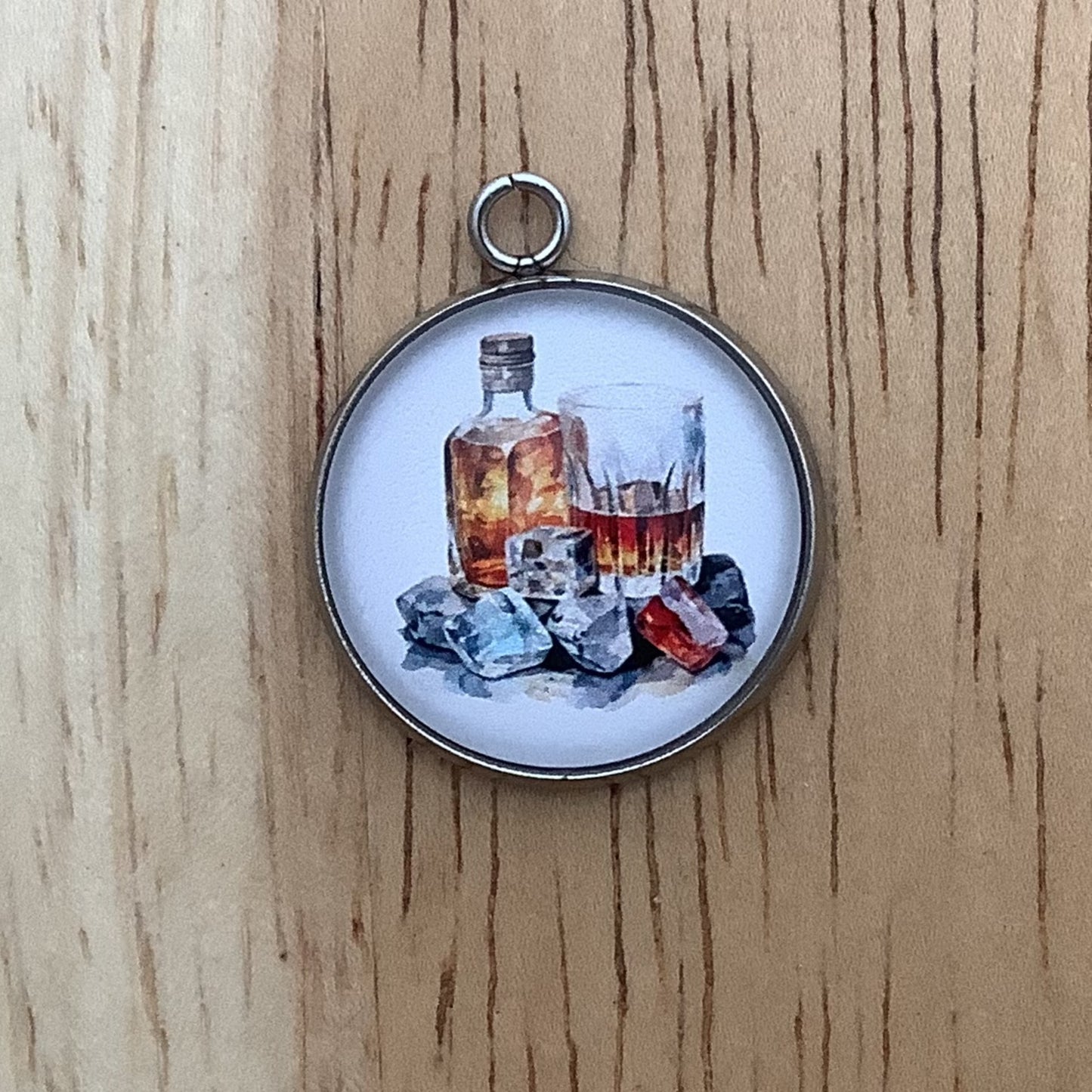 charm depicting a bottle and a glass of brown liquor.