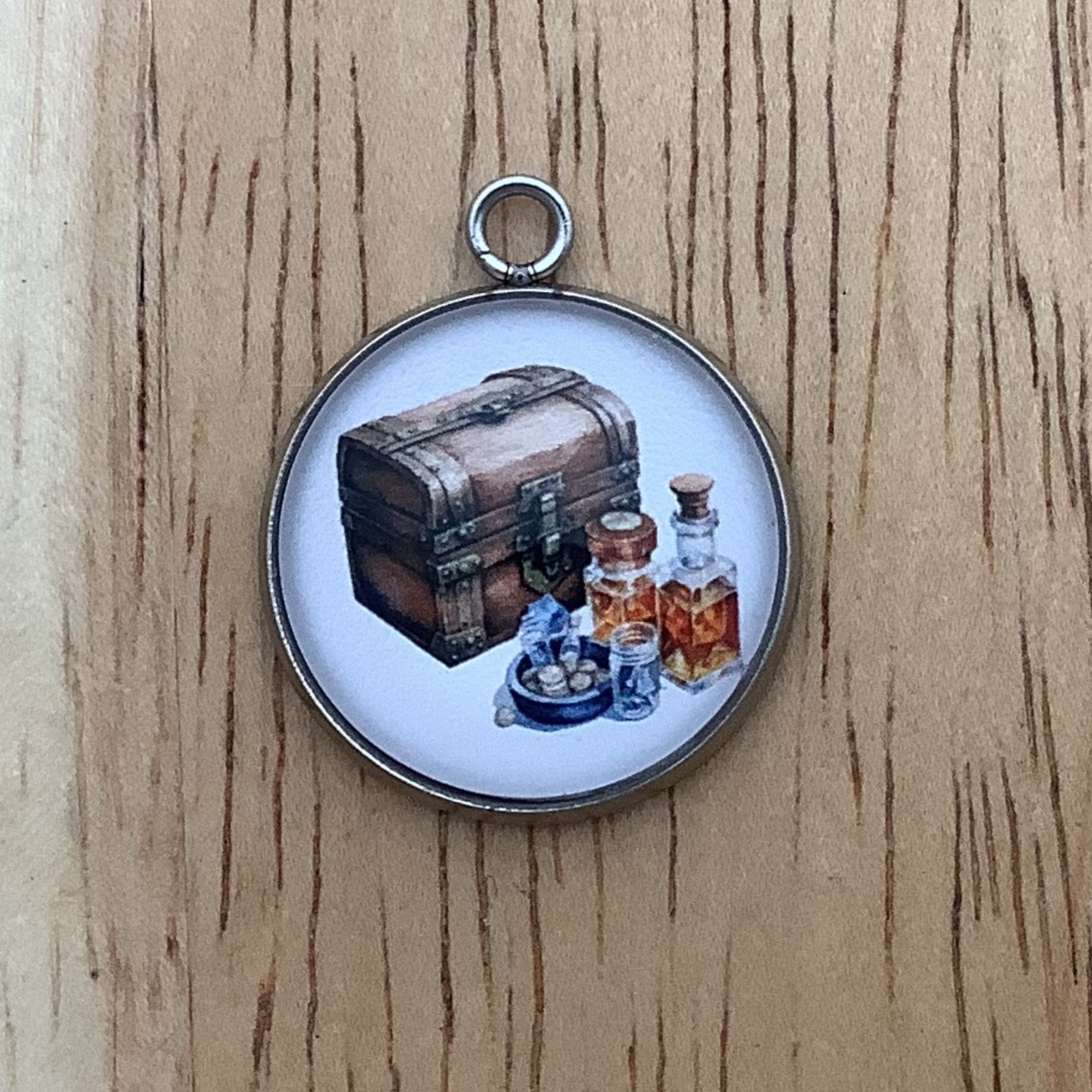 charm depicting a closed storage chest with bottles of brown liquor in front of it.