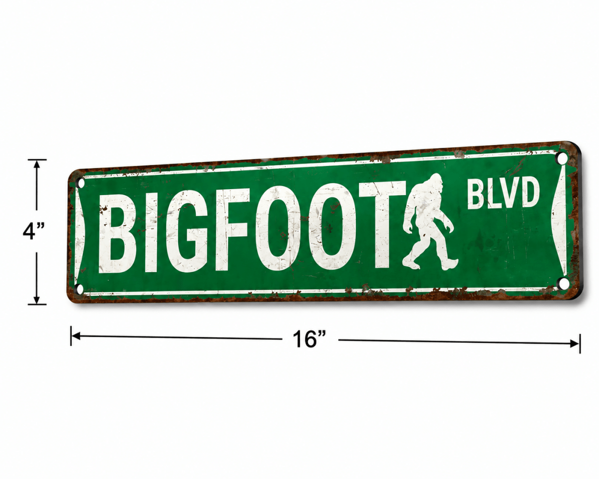 A green street-sign style decorative plaque reading "BIGFOOT BLVD" with a white Bigfoot silhouette, shown on a white background with dimension lines indicating 4 by 16 inches.