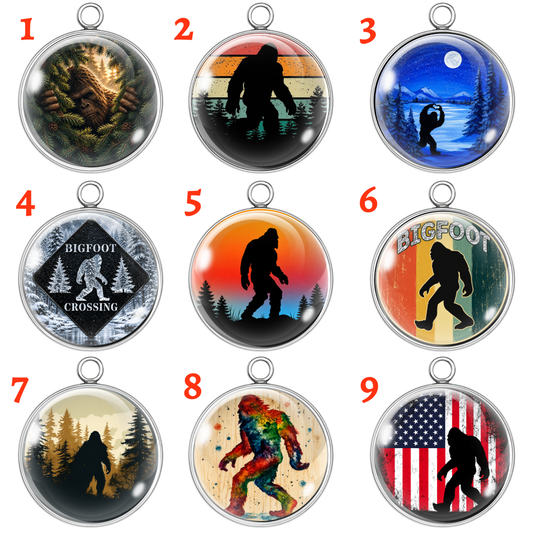 Nine Bigfoot-themed pendants with various designs on a white background.