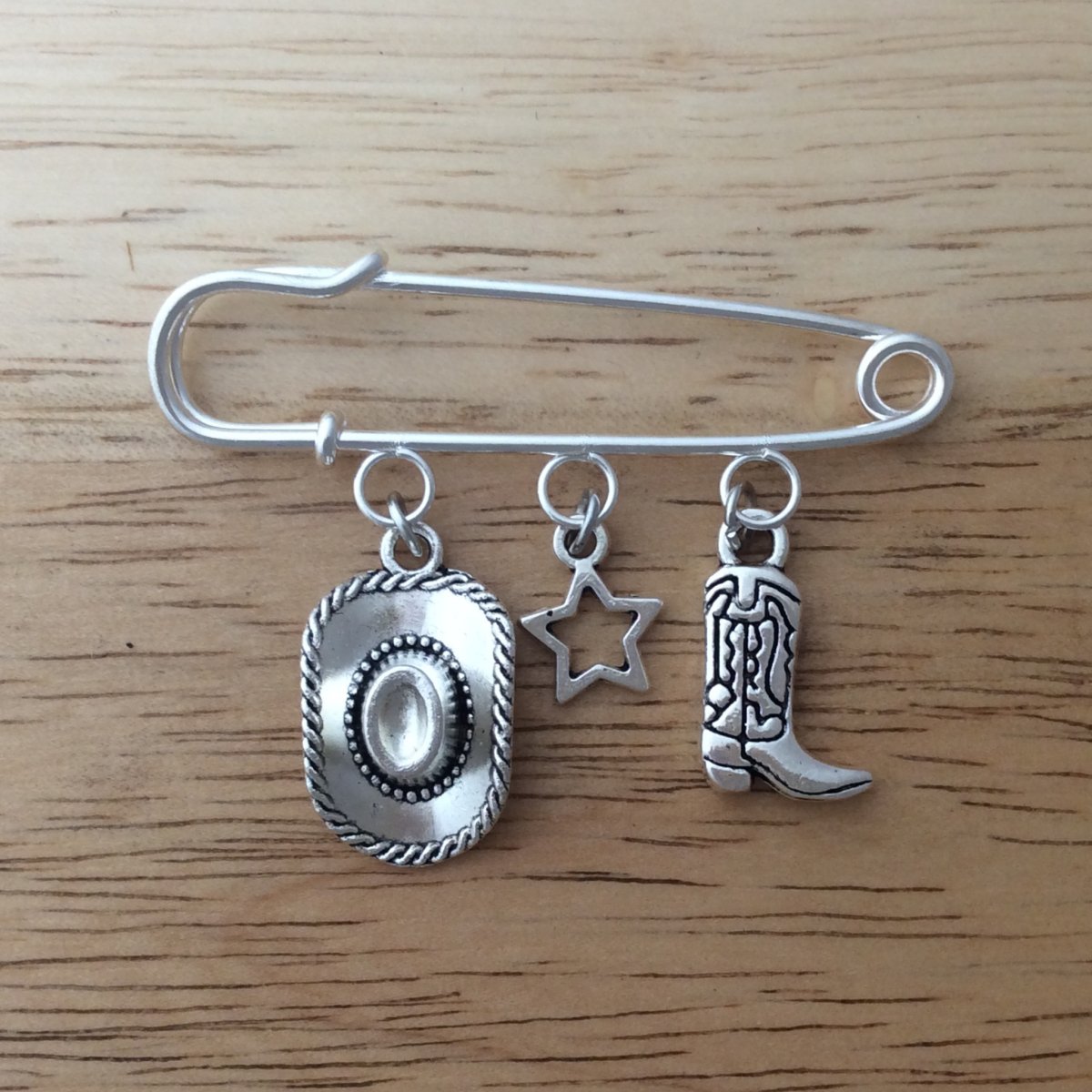 stainless steel lapel pin with a cowboy hat, star and cowboy boot dangle charms