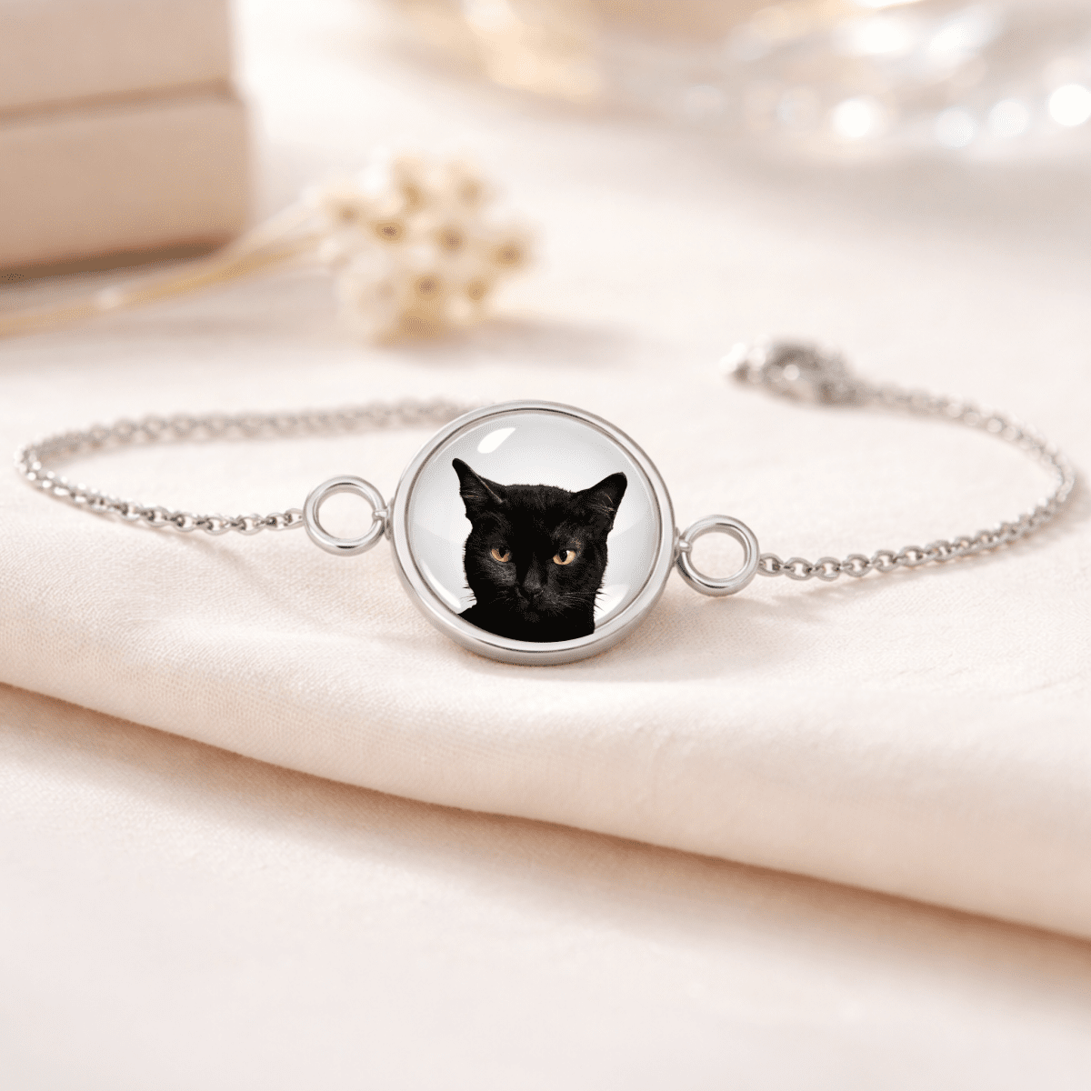 Bracelet with a black cat face charm on a light fabric background