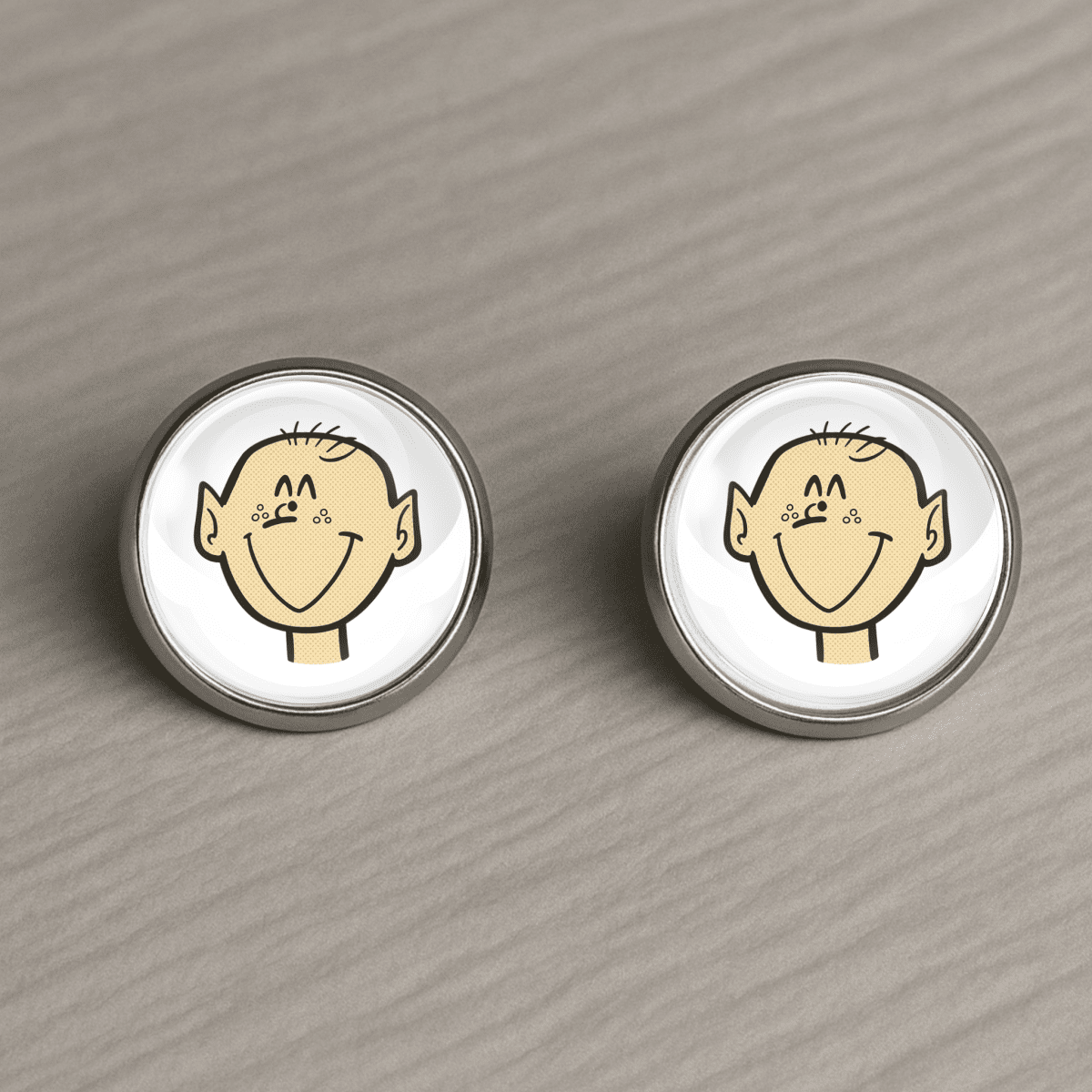 Pair of post earrings with cartoon face design on a wooden surface