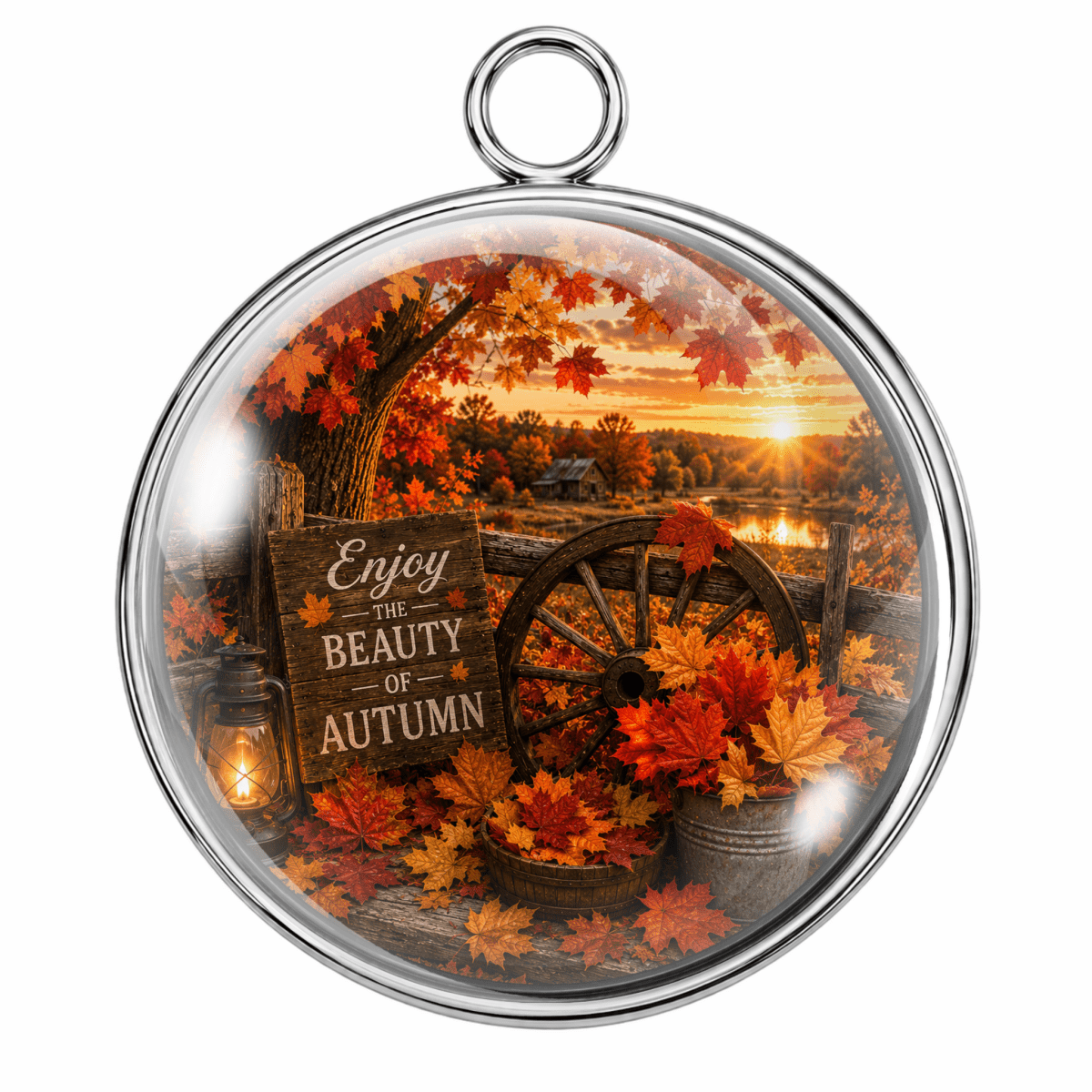 Round silver-toned pendant with a clear domed insert featuring an autumn landscape scene, including orange and red maple leaves, a wagon wheel, a lantern, and a sign that reads 'Enjoy the Beauty of Autumn.'.
