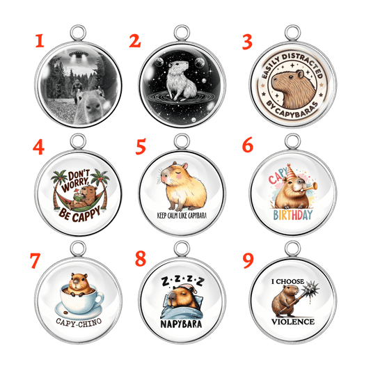 Nine capybara-themed charms with various designs on a white background