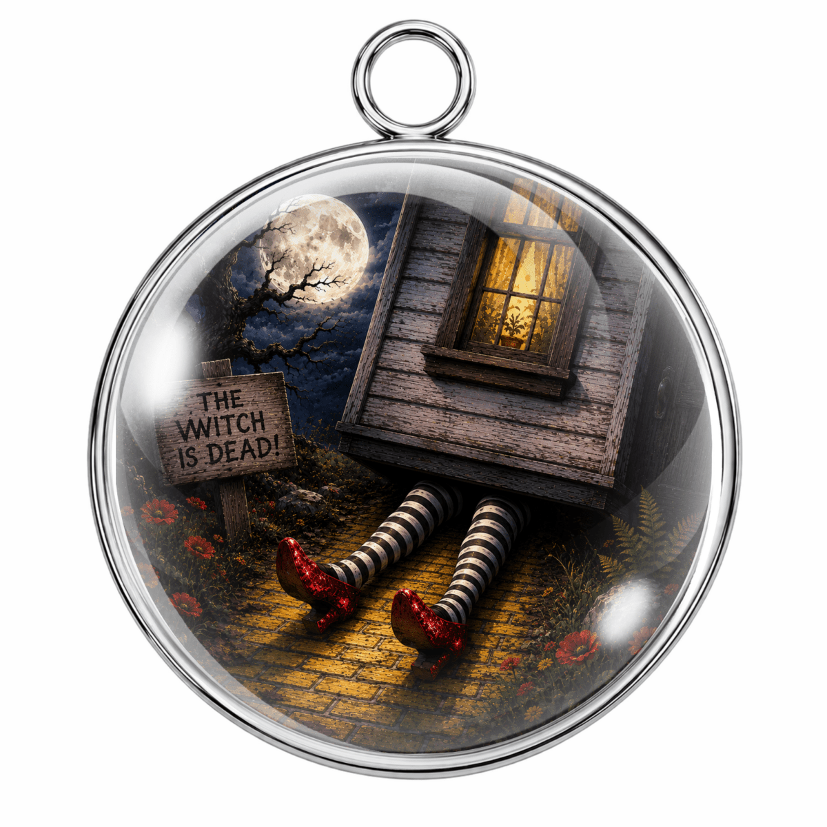 A round glass pendant with a silver metal frame and hanging loop, featuring a gothic horror illustration of a house, striped legs, red shoes, and a sign that reads 'THE WITCH IS DEAD!' on a white background.