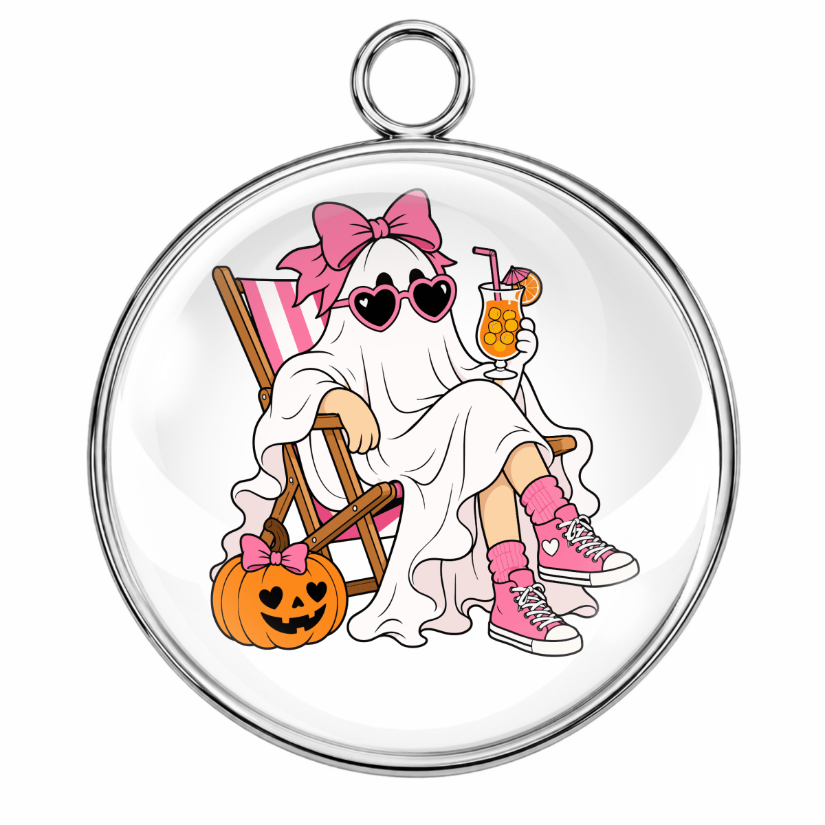 A round glass cabochon charm with a silver metal border and hanging loop, featuring a cartoon illustration of a ghost in a pink bow sitting in a striped chair next to a jack-o'-lantern.