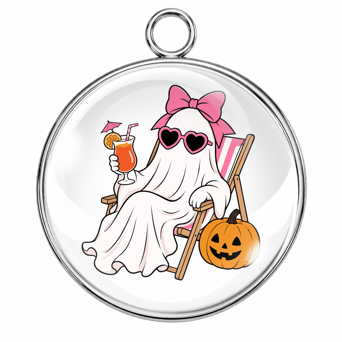 A round silver-toned pendant or charm with a clear domed surface featuring a cartoon ghost lounging in a chair next to a jack-o'-lantern, wearing pink sunglasses and a pink bow, on a plain white background.
