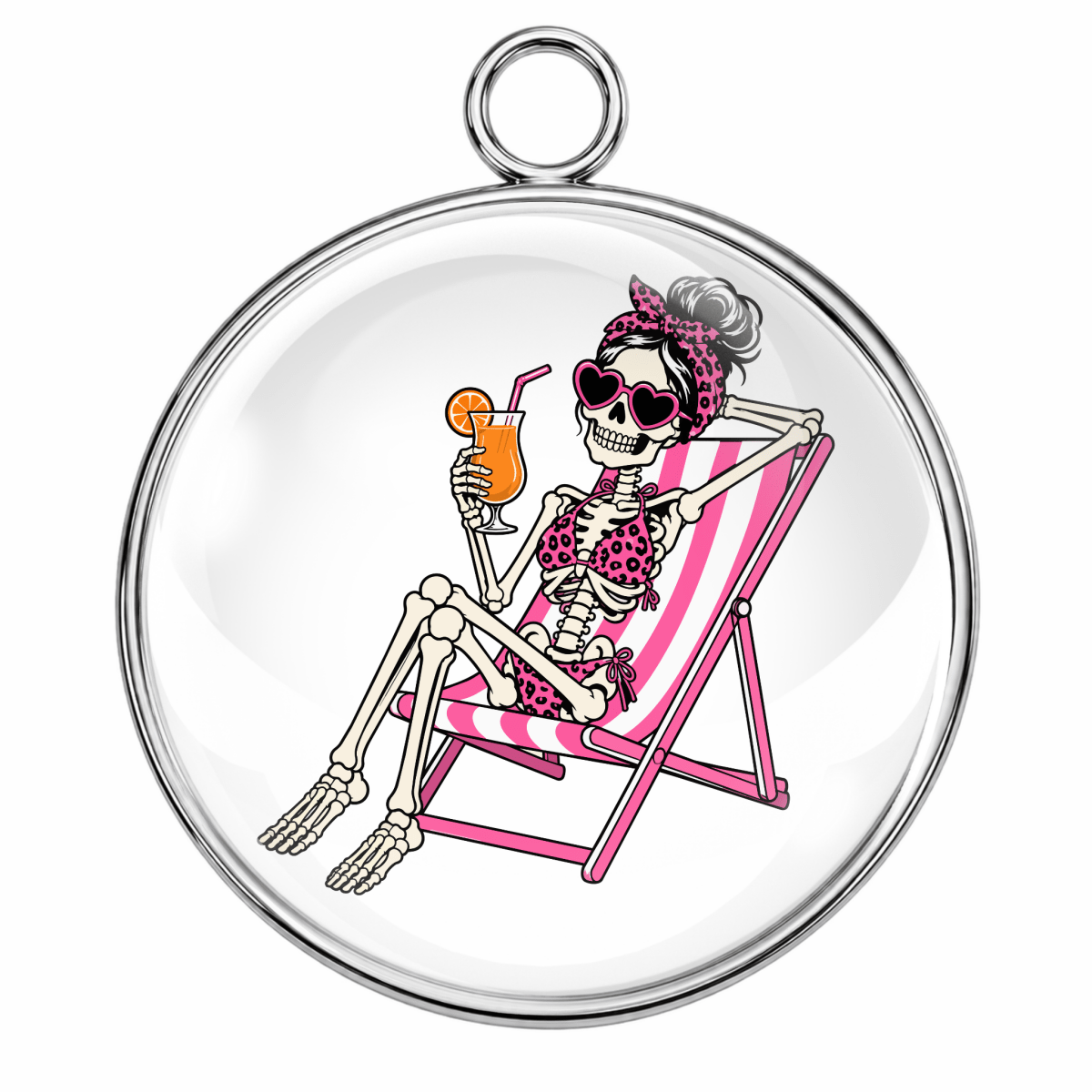 A round silver-toned pendant or charm with a clear glass-like center showing a cartoon skeleton reclining in a pink striped lounge chair and holding an orange drink.