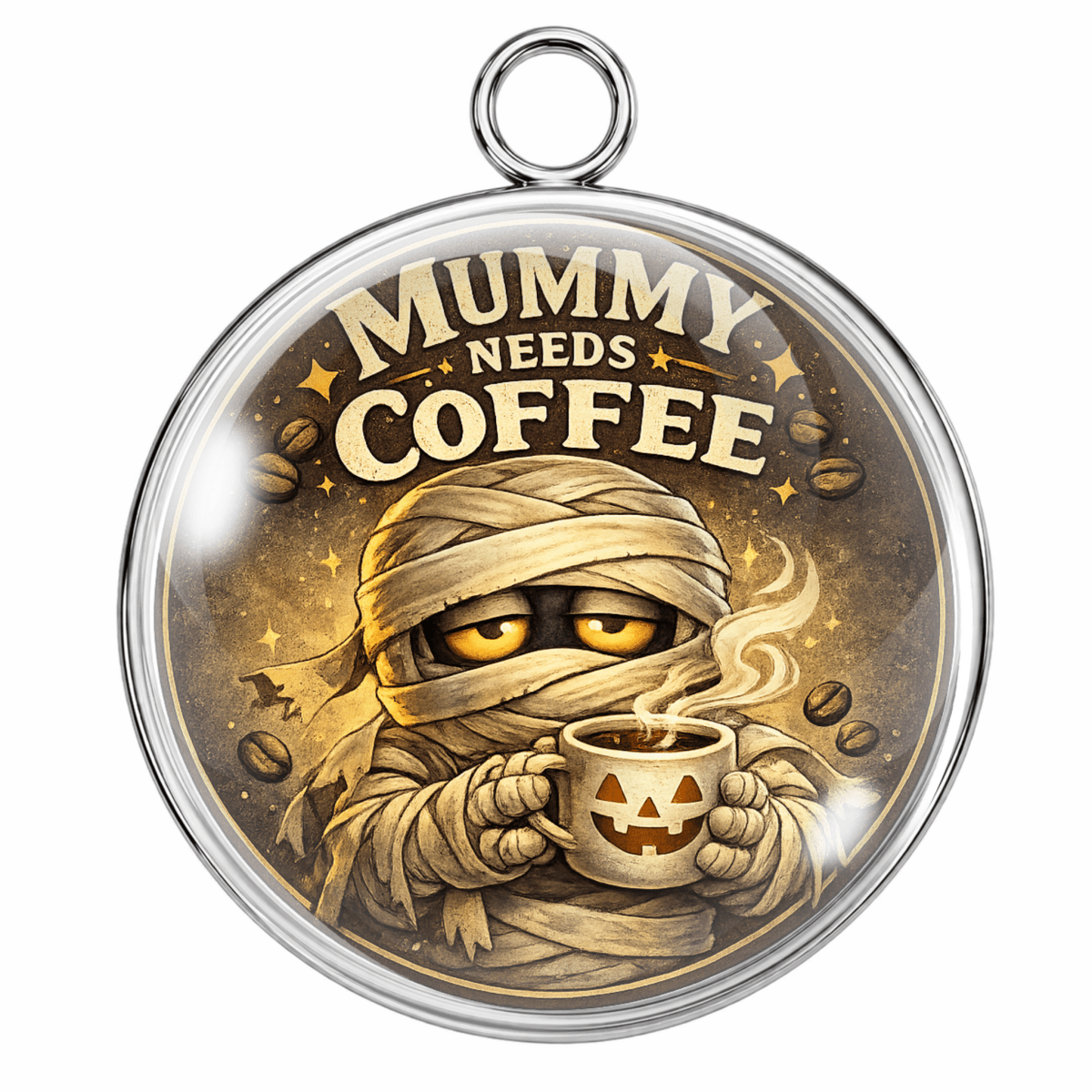 A round pendant or charm with a silver-tone metal border and hanging loop, featuring a mummy wrapped in bandages holding a jack-o'-lantern coffee cup, with the text 'MUMMY NEEDS COFFEE' on a warm brown background.