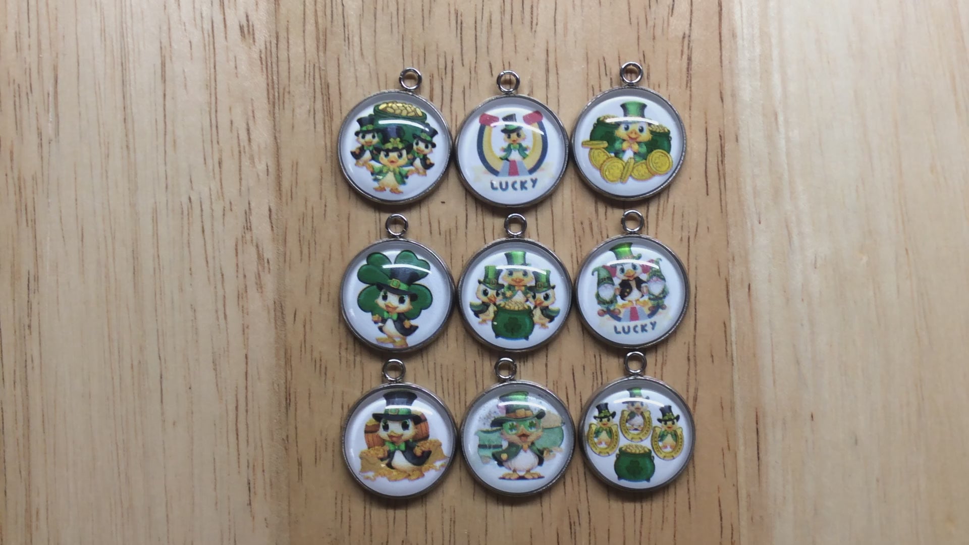 video of 9 glass cabochon charms with ducks in st Patricks clothing in front of gold