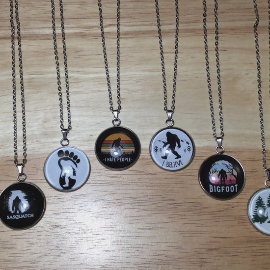 Video of six stainless steel glass cabochon  necklaces with various scenes of bigfoot