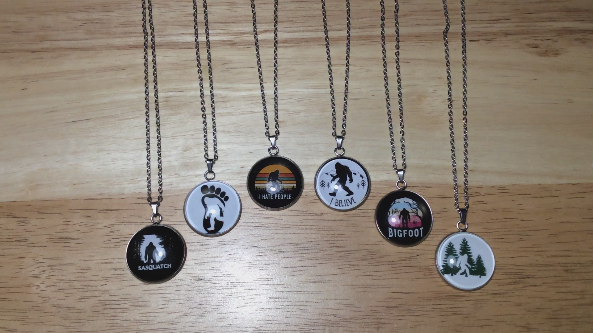 Video of six stainless steel glass cabochon  necklaces with various scenes of bigfoot