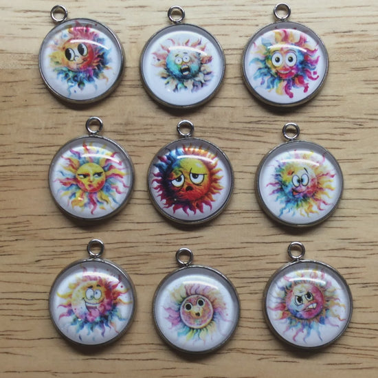 video of 9 Glass cabochon charms with a funny faced, rainbow colored sun