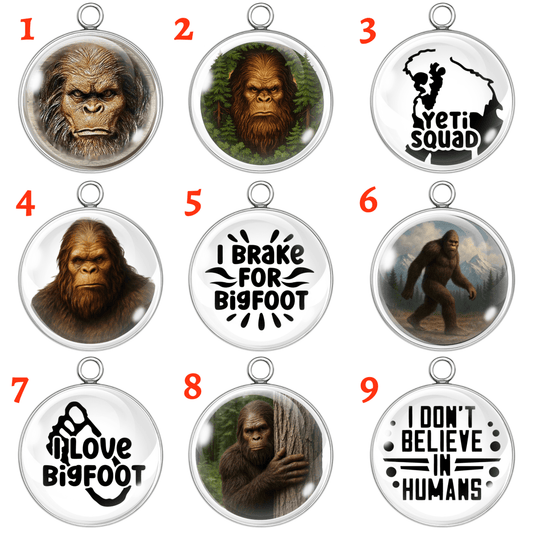Set of 9 Bigfoot-themed glass cabochon charms with various Sasquatch illustrations and funny sayings, handmade in stainless steel settings