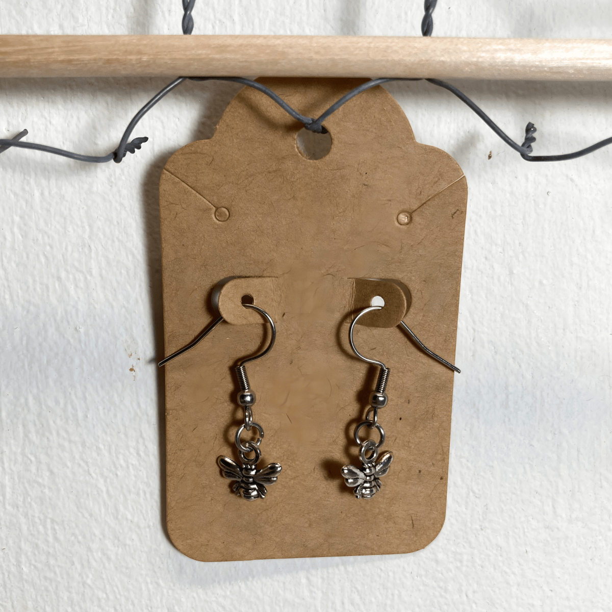 Bee-shaped earrings on a cardboard backing with a white background