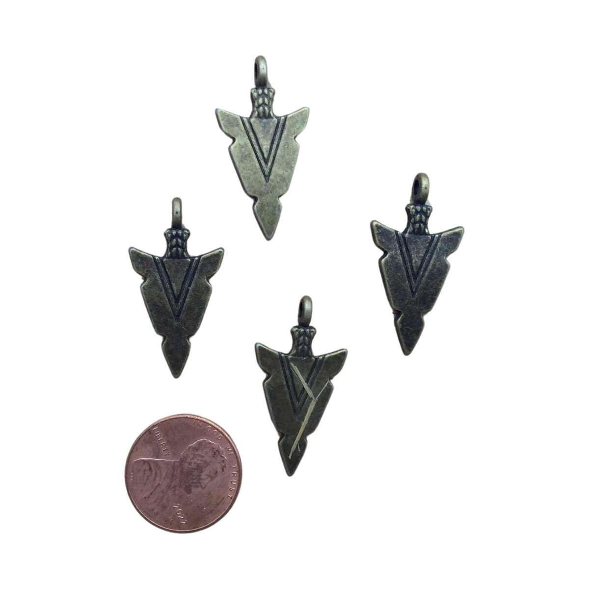 4 bronze arrowhead charm pendants next to a penny for size