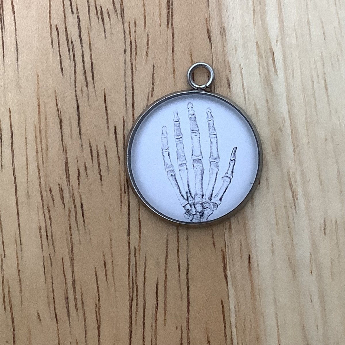 a charm featuring a drawing of a human hand