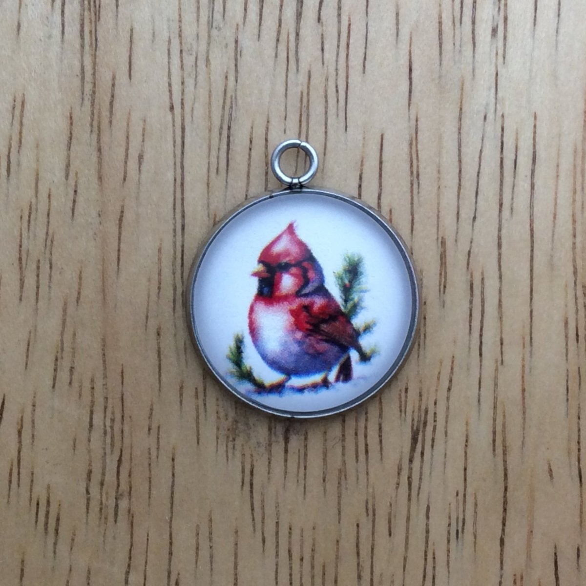 glass cabochon charm with a red cardinal perched on a pine branch