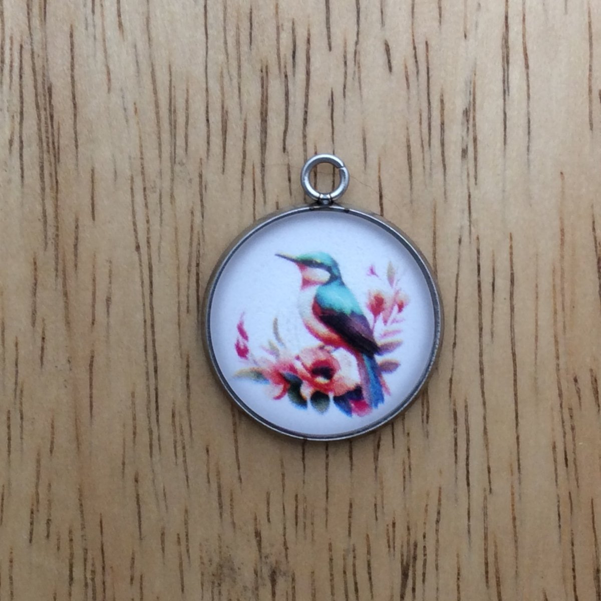 glass cabochon charm with a beautiful bird perched on a branch of flowers