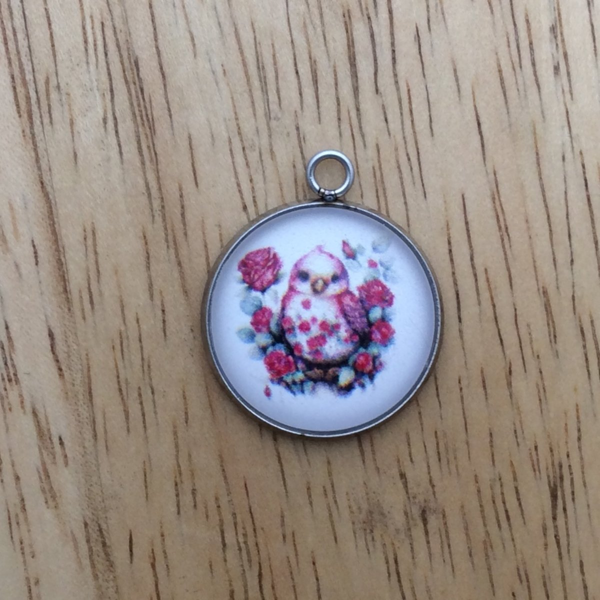 glass cabochon charm with a beautiful bird sitting among flowers