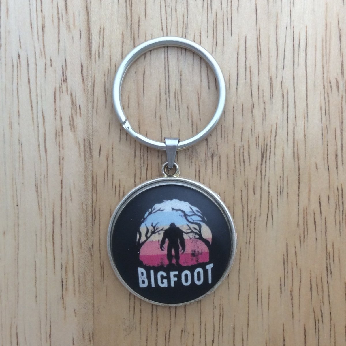 Tibetan silver glass cabochon keyring with a bigfoot walking through the trees and says "Bigfoot"