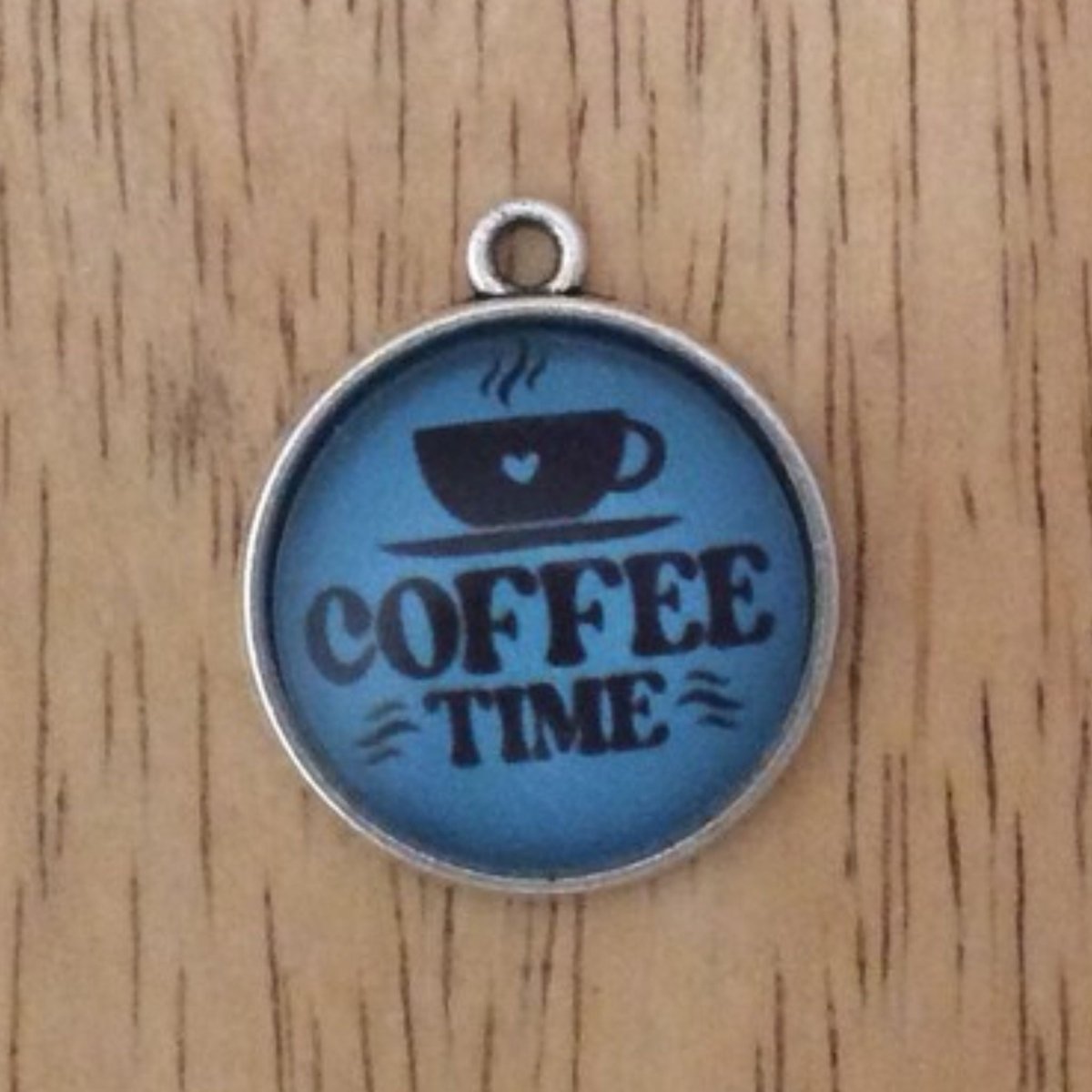 glass cabochon charm that says coffee time with a black coffee cup on a blue background