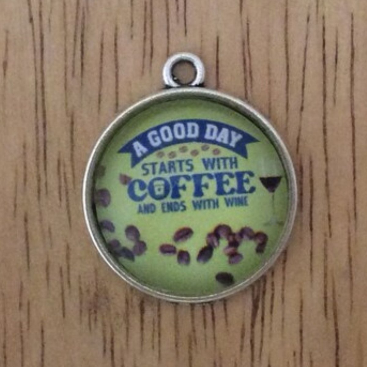 glass cabochon charm that says a good day starts with coffee and ends with wine, with a wine glass half full among scattered coffee beans