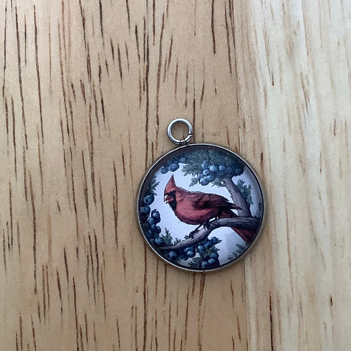 a charm of a cardinal on a branch of a juniper bush with lots of small blue berries