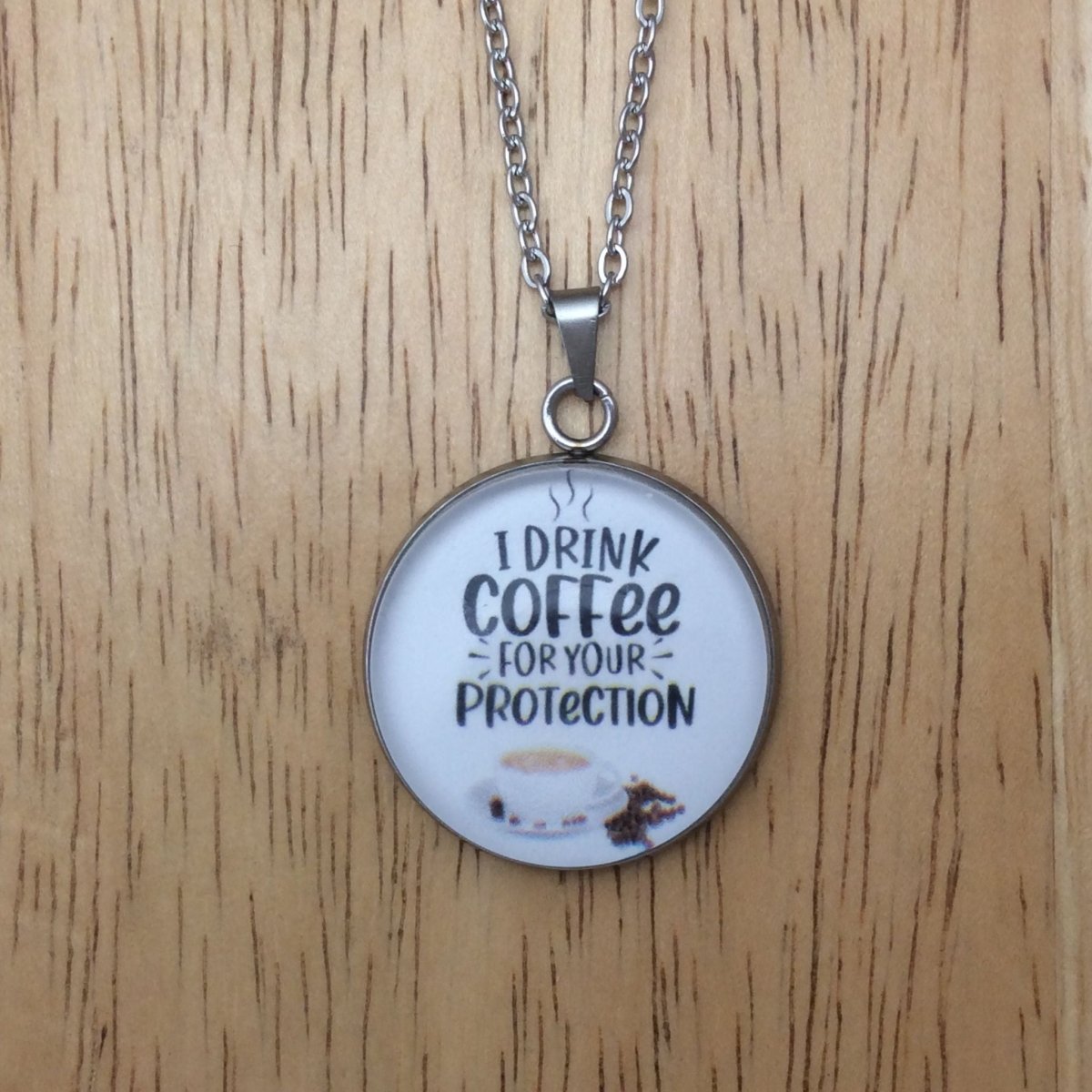 Stainless steel glass cabochon necklace that says "I Drink Coffee for your protection"