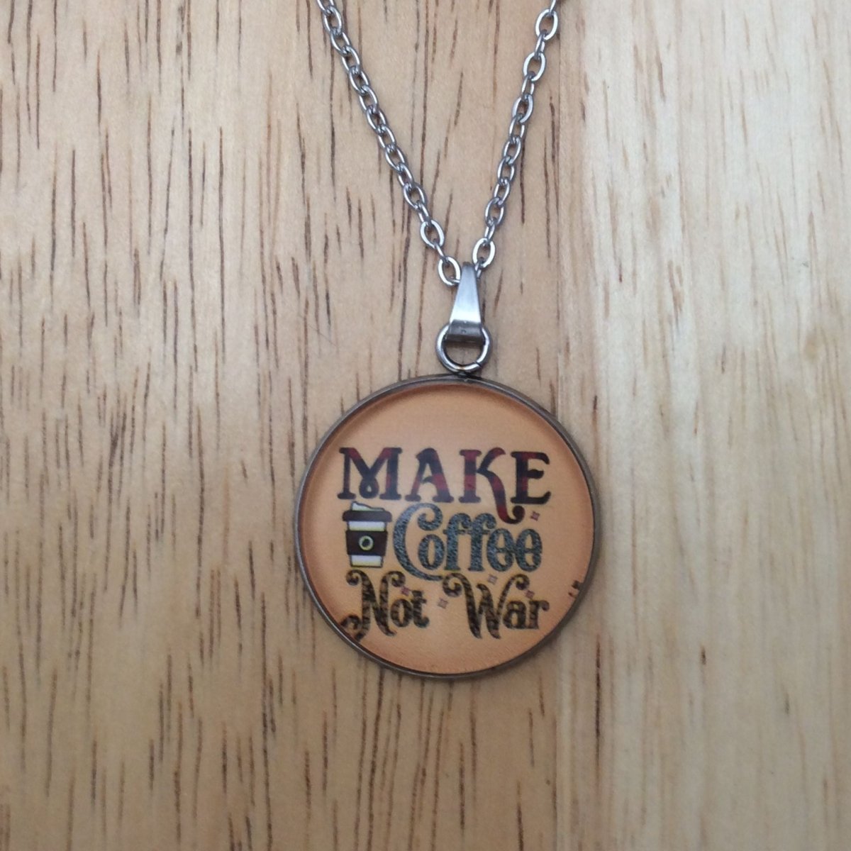 Stainless steel glass cabochon necklace that says "Make coffee not war"