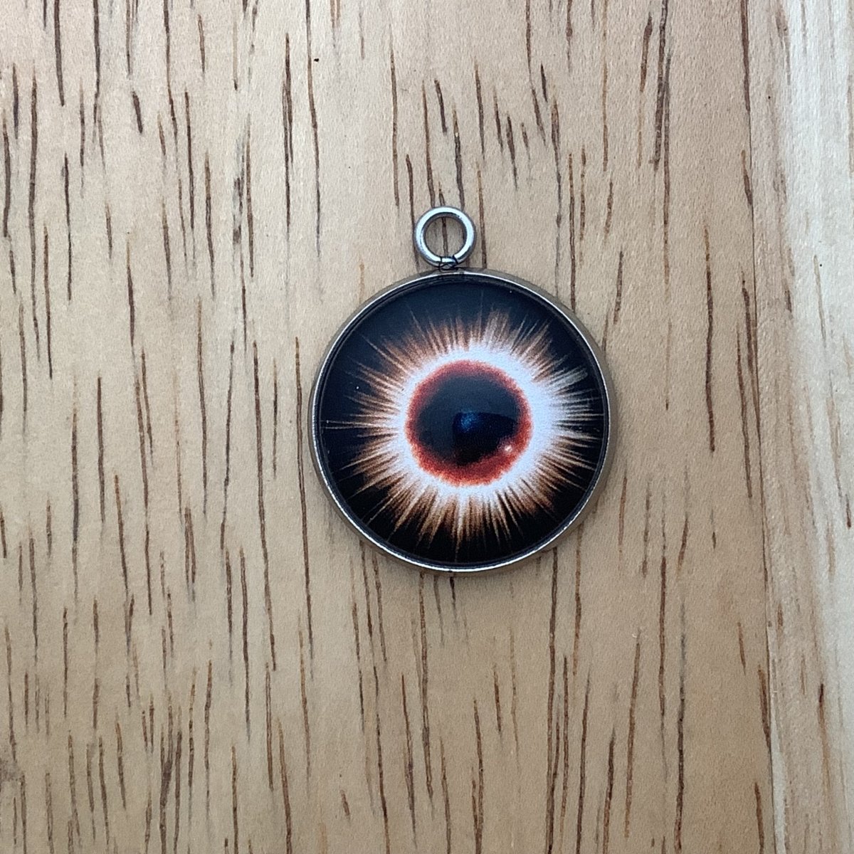 a charm depicting an eclipse with a bright starbust design behind