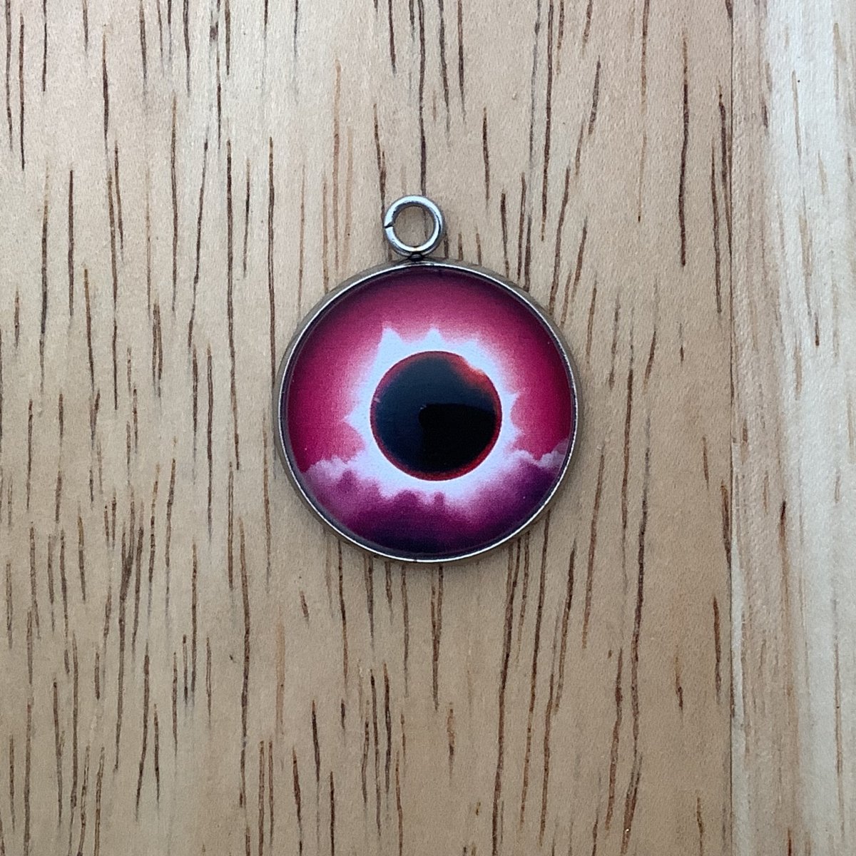 a charm depicting an eclipse with a red background