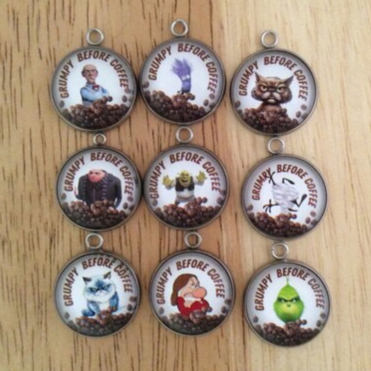 set of 9 glass cabochon charms that have various characters over a pile of coffee beans and it says Grumpy Before Coffee