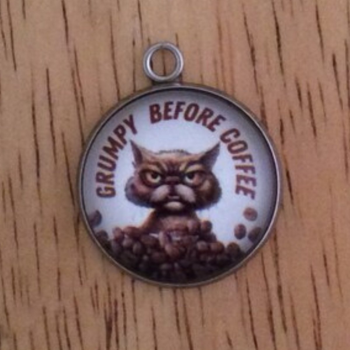 glass cabochon charm with a grouchy cat behind a pile of coffee beans and it says Grumpy Before Coffee